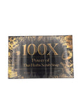 Black and gold box of Jennie Moon 100X Power of Thai Herbs Scrub Soap, with a large gold 100X and gold botanical line art of Thai herbs, flowers and roots framing the panel